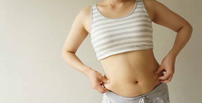 お腹の肉をつまむ女性